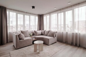 A modern living room with a sofa set, a coffee table, and sheer curtains. - 2BR Penthouse Rotterdam City Centre (Rotterdam)