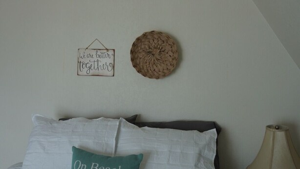 A bedroom with a bed, pillows, a wall-mounted basket, a sign, and a lamp. - Lakefront Retreat w/Dock +Walk to Surf District (Clear Lake)