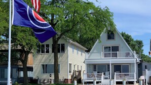 A waterfront property with a dock, a house with a balcony, and a flagpole with a flag. - Lakefront Retreat w/Dock +Walk to Surf District (Clear Lake)