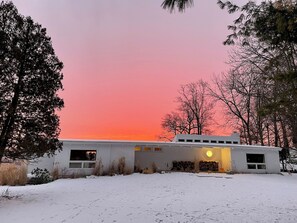 A single-story building with a flat roof, surrounded by snow-covered ground and trees.