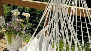 A hammock on a wooden deck overlooking a calm river with boats, surrounded by lush greenery. - Luxury Mid Century Home on Hudson Waterfront Bluff. 4 bed/3 bath (Highland)