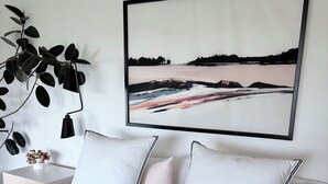 A bedroom with a bed, pillows, a bedside table with a plant, and a wall-mounted painting. - Luxury Mid Century Home on Hudson Waterfront Bluff. 4 bed/3 bath (Highland)