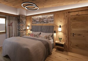 Un dormitorio con pared de piedra, paneles de madera, una cama con muchos almohadones y una mesita de noche con una planta.