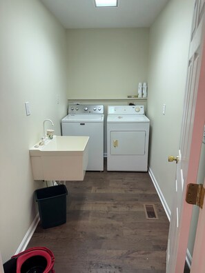 Une buanderie équipée de deux machines à laver, d’un évier et d’une poubelle.
