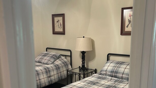 A bedroom with two beds, a ceiling fan, and wall-mounted lamps. - Quiet, serene 3-bedroom house with in charming Owingsville, Kentucky. (Owingsville)