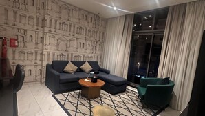 A modern living room with a sectional sofa, a coffee table, and a patterned floor. - Business Bay Hotel Apartment (Dubai)