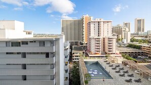 Un hotel de varios pisos con una zona de piscina en la azotea, rodeado de edificios altos.