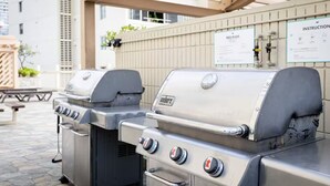 Una parrilla para barbacoa con panel de control y conducto de ventilación, ubicada al aire libre bajo una pérgola.