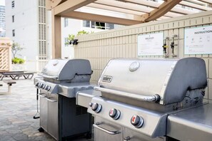 Een barbecue met bedieningspaneel en ventilatie, buiten geplaatst onder een pergola.