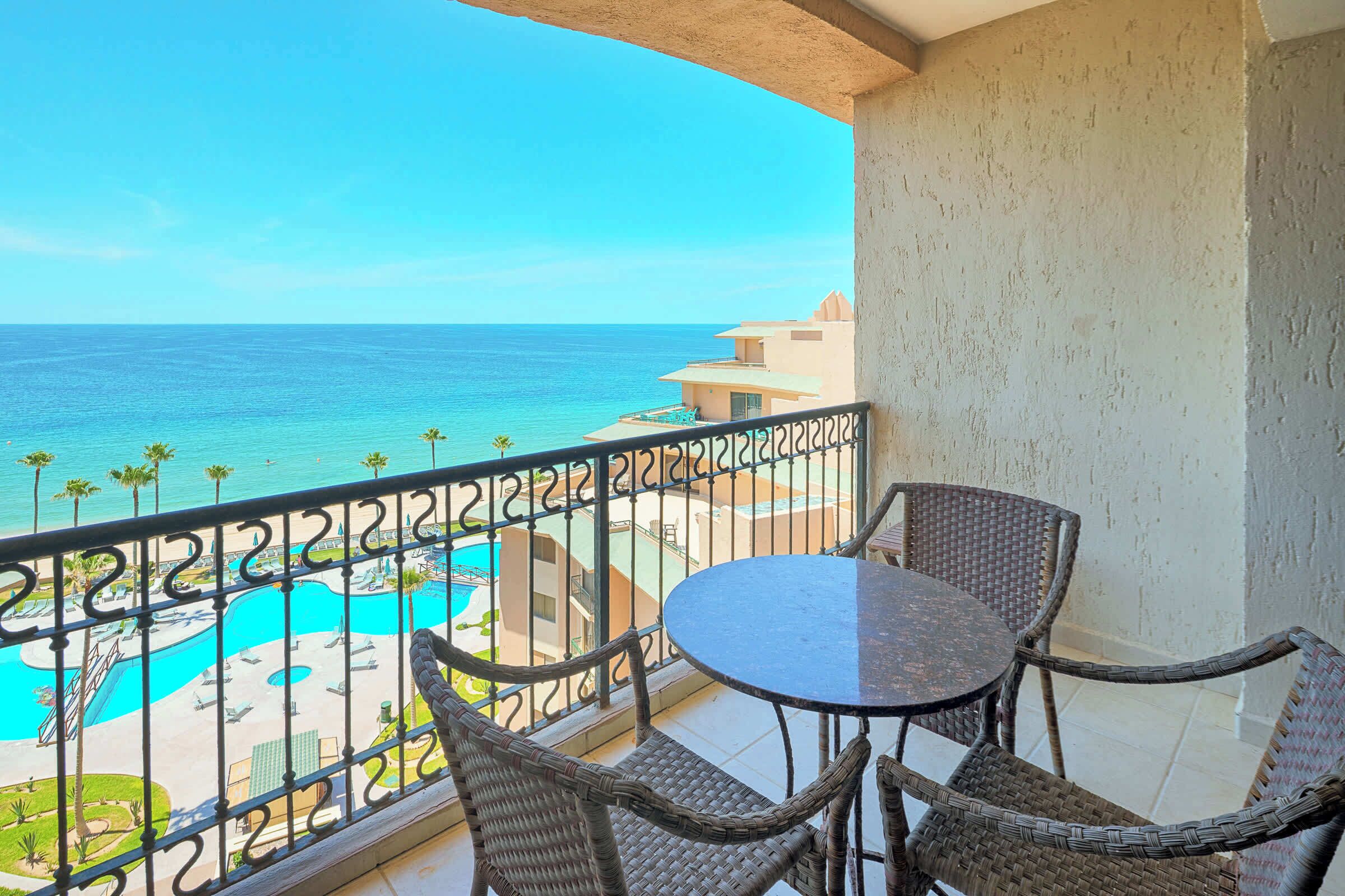 A balcony with a view of a pool and ocean.