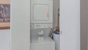A compact laundry room with a washing machine, a dryer, and a small shelf with a cup. - Beachfront 1BR Penthouse Sonoran Spa N805 (Puerto Peñasco)