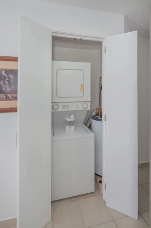 A compact laundry room with a washing machine, a dryer, and a small shelf with a cup. - Beachfront 1BR Penthouse Sonoran Spa N805 (Puerto Peñasco)