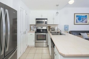 A compact kitchen with stainless steel appliances, white cabinetry, and a tiled backsplash. - Beachfront 1BR Penthouse Sonoran Spa N805 (Puerto Peñasco)