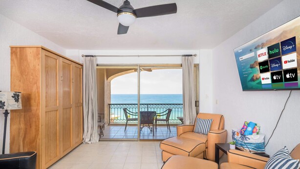 A living room with a sofa, a TV mounted on the wall displaying streaming services, and a balcony with a view of the sea. - Beachfront 1BR Penthouse Sonoran Spa N805 (Puerto Peñasco)