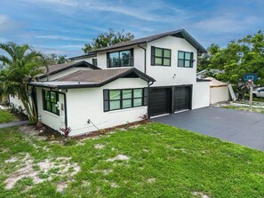 Ein zweistöckiges Haus mit Garage, Auffahrt und Basketballkorb.