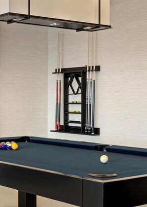 A pool table with balls and cues, a wall-mounted cue rack, and a billiard table. - Cozy 1-bedroom apartment in fantastic Raleigh with AC and gym access (Raleigh)