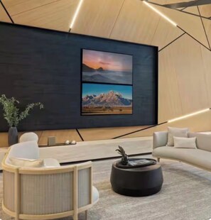 A modern living room with a large wall-mounted TV, a sofa, a coffee table, and a potted plant. - Cozy 1-bedroom apartment in fantastic Raleigh with AC and gym access (Raleigh)