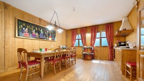 A wooden interior with a dining table, chairs, a painting, and a kitchen area. - Papavero Room with Mountain View, Shared Garden and Wi-Fi (Bivedo-Larido-Marazzone)