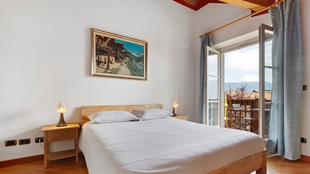 A bedroom with a bed, bedside lamps, a painting on the wall, and a balcony with a view. - Papavero Room with Mountain View, Shared Garden and Wi-Fi (Bivedo-Larido-Marazzone)