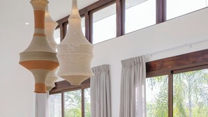 Ein moderner Essbereich mit einem großen Holztisch, mehreren Stühlen und hängenden Gewebeleuchten.