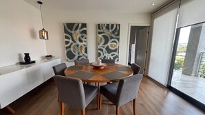 Een moderne eetruimte met een ronde tafel, zes stoelen en abstracte wanddecoratie.