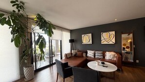 Een moderne woonkamer met een hoekbank, een eettafel en een grote kamerplant.