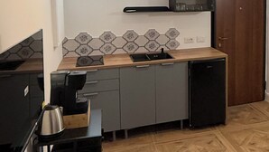 Uma cozinha compacta com micro-ondas integrado, um frigorífico pequeno e uma pia.