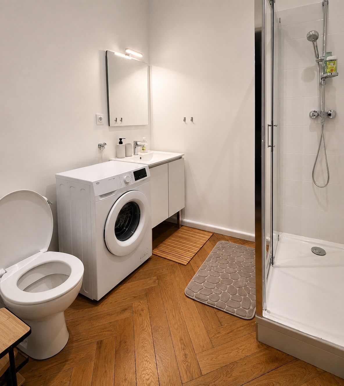 Une salle de bain moderne équipée d’un lave-linge, de toilettes et d’une douche.