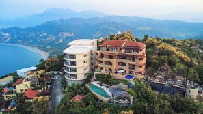 Un hotel a più piani con piscina e vista sulla costa.