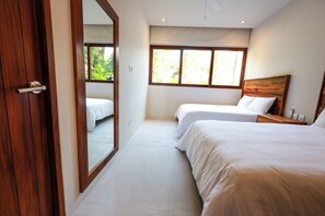 A hotel room with two beds, a large window, and a wooden door.