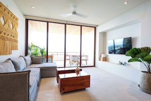 A modern living room with a sofa, coffee table, and a TV. - Ocean View Two-Bedroom Villa at Cerro del Vigia (Zihuatanejo)