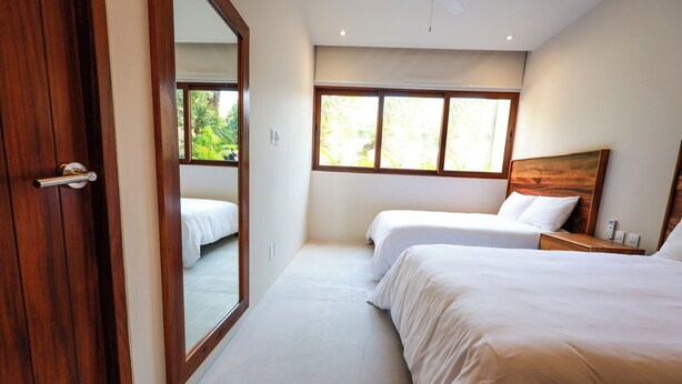 Ein Schlafzimmer mit zwei Betten, einer Holztür und einem großen Fenster.