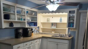 A kitchen with white cabinets, a built-in sink, a ceiling fan, and a backsplash.