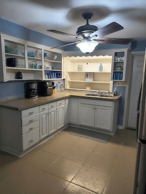 A kitchen with white cabinets, a built-in sink, a ceiling fan, and a backsplash.
