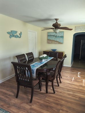 A dining area with a wooden table, chairs, and a ceiling fan.