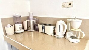 En köksbänk med en mixer, en juicer, en matberedare, en brödrost, en vattenkokare och en kaffebryggare.