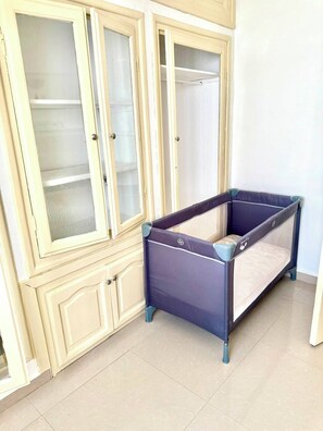 Une pièce avec une grande armoire, un petit lit et un sol carrelé.