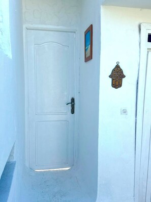 A white door with a handle, a small framed picture, and a decorative hanging ornament on the wall. - Family villa with no neighbors directly across the street, 5 minutes from the beach - Sidi Bouzid (Sidi Bouzid)