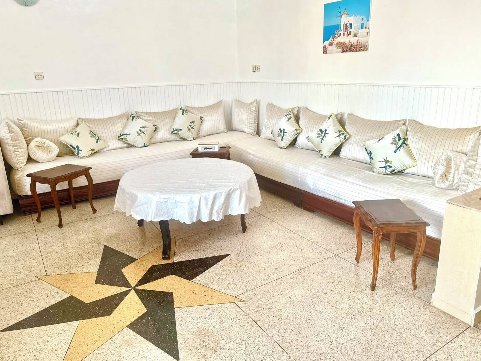 A room with a sofa, a round table, and a star-patterned floor.