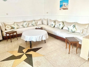 Une pièce avec un canapé, une table ronde et un sol orné d’un motif en étoile.