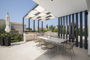 An outdoor patio with a table and chairs, a grill, and potted plants. - Villa BB near Rovinj (Bale)