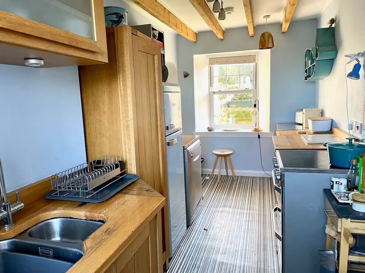 A modern kitchen with wooden cabinets, a built-in dishwasher, a sink, and a window providing natural light.