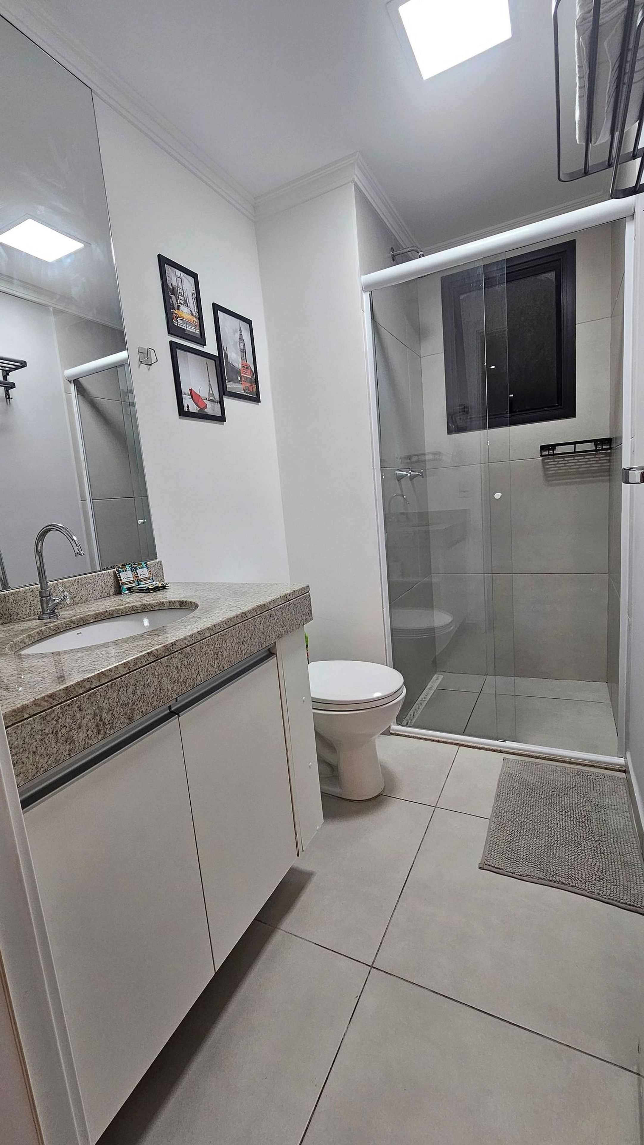 Un baño moderno con lavamanos, inodoro y ducha con mampara de vidrio.