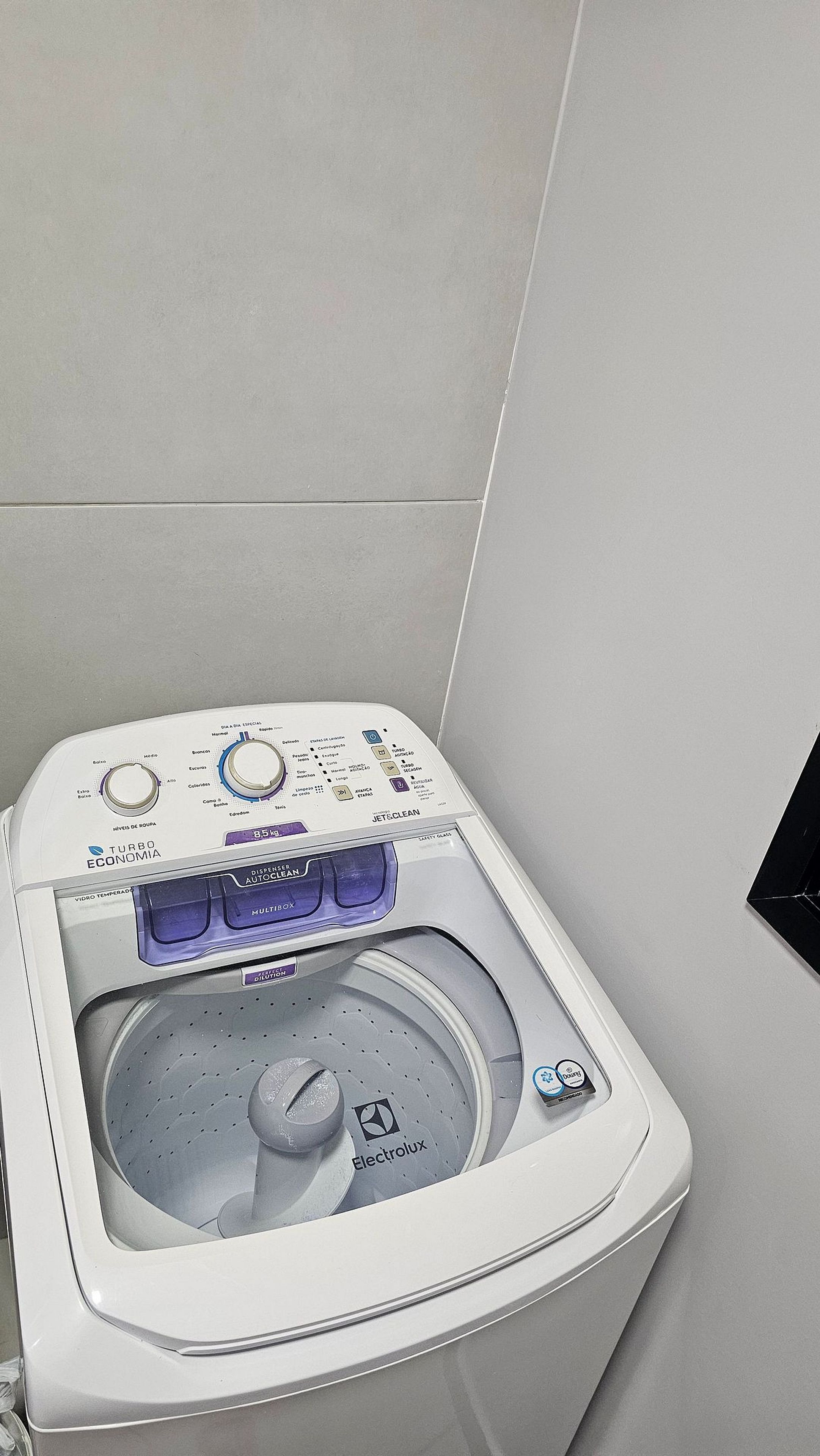 Máquina de lavar roupa branca e moderna, fixada na parede, com painel de controlo digital e tambor transparente.