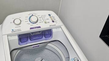 Máquina de lavar roupa branca e moderna, fixada na parede, com painel de controlo digital e tambor transparente.