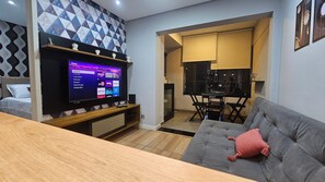 Uma sala de estar moderna com televisão de tela plana, sofá cinza, mesa de centro de madeira e parede com padrão.