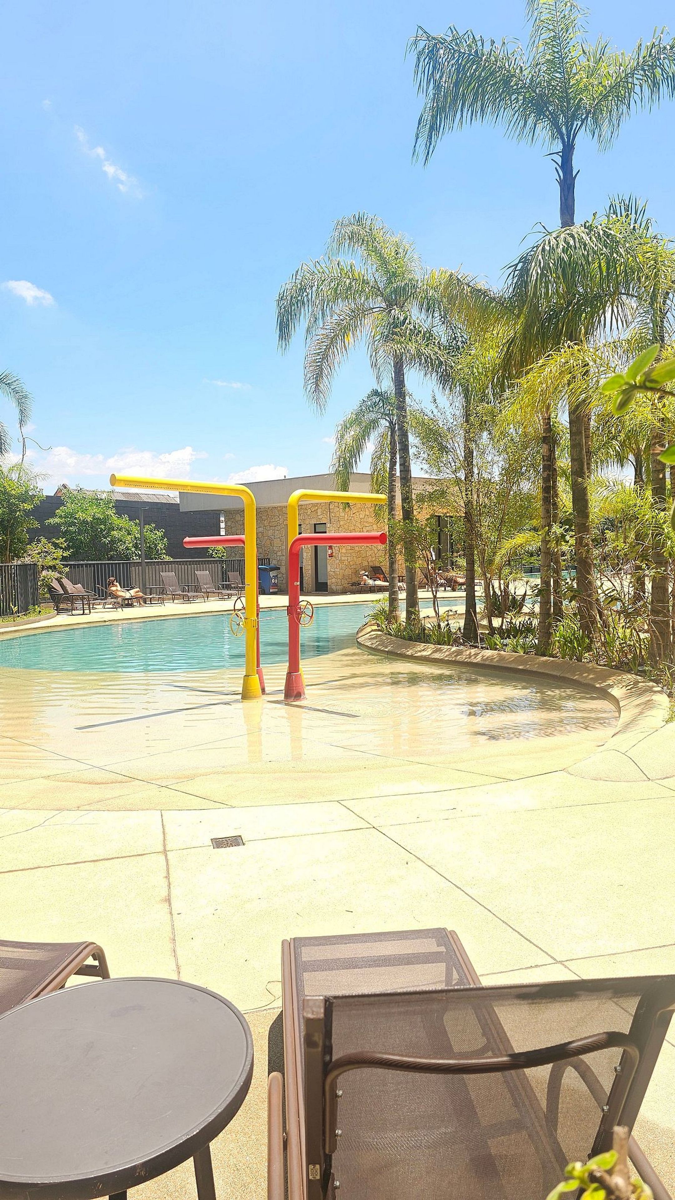 A pool area with lounge chairs and a water play structure.
