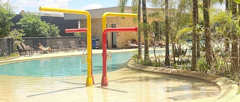 A pool area with lounge chairs and a water play structure.