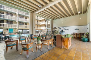 Un área de piscina interior con mobiliario de madera y vistas a los balcones del edificio.