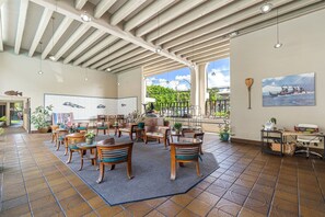 A spacious indoor area with wooden furniture, a tiled floor, and a view of the outdoors. - Banyan's Bungalow at The Kona Bali Kai (Kailua-Kona)